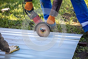 A worker is cutting metal to install a fence