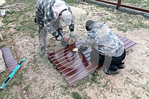 A worker is cutting metal to install a fence