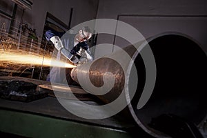 Worker cutting pipe with angle grinder.