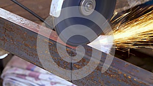 Worker cutting rectangular steel tube with an angle grinder tool creating sparks