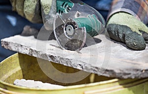 Worker cutting roof tiles with circular saw machine