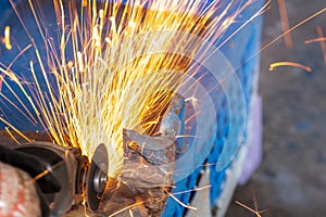 Worker cutting steel with grinding machine and splashes of sparks in workshop