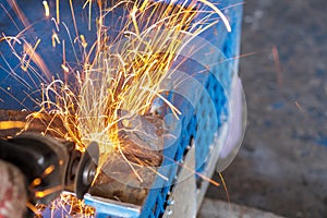 Worker cutting steel with grinding machine and splashes of sparks in workshop