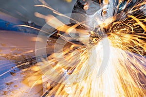 Worker cutting steel with grinding machine and splashes of sparks in workshop
