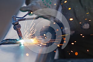 Worker cutting steel pipe using metal torch and install roadside