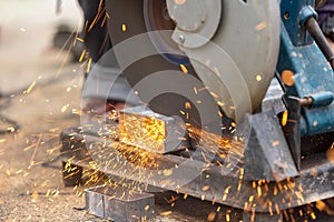 Worker cutting steel rectangular pipe in construction site