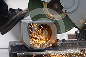 Worker cutting steel rectangular pipe in construction site