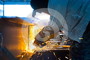 Worker cutting steel structure with angle grinding.