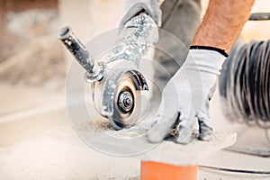 Worker cutting stone with grinder. Dust while grinding stone pavement