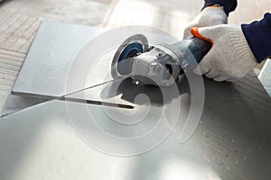 Worker cutting a tile using an angle grinder at construction sit