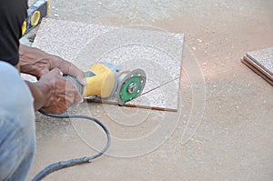 worker cutting a tile by using an angle grinder on the floor