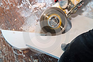 Worker cutting tile using grinder cut into layers of ceramic floor tiles