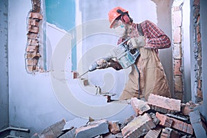 Worker with demolition hammer breaking interior wall