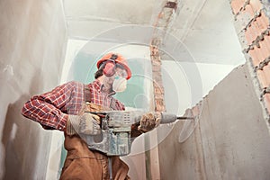 Worker with demolition hammer breaking interior wall