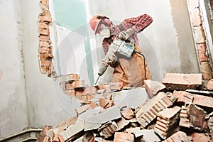 Worker with demolition hammer breaking interior wall