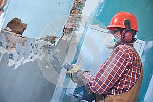 Worker with demolition hammer breaking interior wall