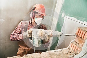 Worker with demolition hammer breaking interior wall