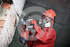 Worker with demolition hammer breaking interior wall