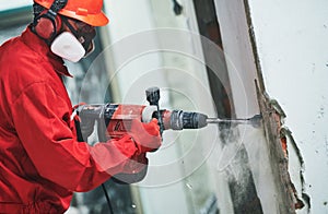 Worker with demolition hammer removing plaster or stucco from wall