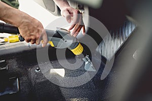 worker, detailer vacuuming carpet of car interior, using steam vacuum