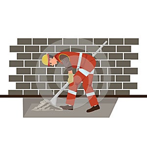 Worker digging with a shovel next to the brick wall. Construction concept