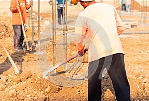 Worker digs soil with spade prepare around pole stucture