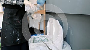 Worker in dirty apron pours detergent into washing machine