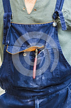 The worker in dirty jeans boilersuit, side cuts or nippers in a pocket, special clothes abstract background