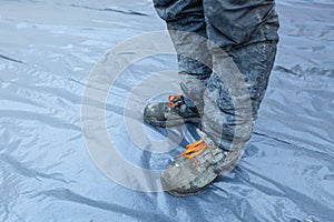 Worker in dirty uniform and shoes with orange laces is staying in construction site. Concept of diry and hard work during