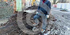 Worker in dirty uniform and shoes with orange laces is staying in the stone in construction site. Concept of diry and hard work