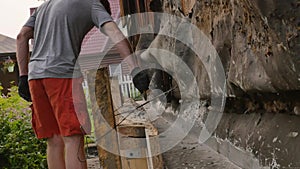 Worker dismantles the wooden formwork, new foundation for old house. 4K