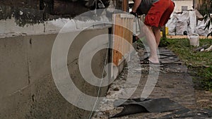 Worker dismantles the wooden formwork, new foundation for old house. 4K