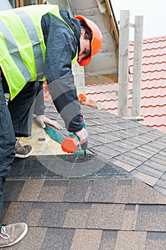 Worker dismantling roof shingles