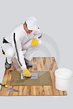 Worker DIY tile adhesive trowel wooden floor
