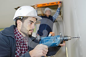 Worker drilling concrete wall construction site