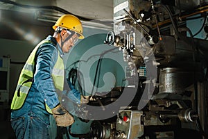 Worker Drilling machine hole metal flat steel plate and selective focus with bench drill in the factory