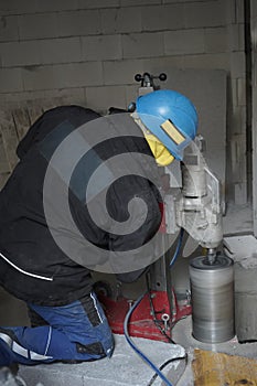 a worker drills a concrete main deme with a huge core drill