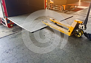 Worker driving forklift loading shipment carton boxes and goods on wooden pallet at loading dock from container truck to warehouse