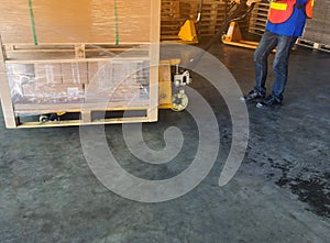 Worker driving forklift loading shipment carton boxes and goods on wooden pallet at loading dock from container truck to warehouse