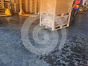 Worker driving forklift loading shipment carton boxes and goods on wooden pallet at loading dock from container truck to warehouse