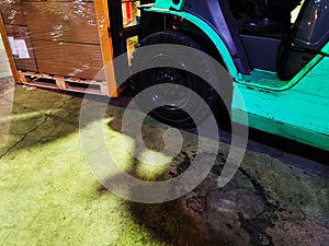 Worker driving forklift loading shipment carton boxes goods on wooden pallet at loading dock from container truck to warehouse