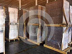 Worker driving forklift loading shipment carton boxes goods on wooden pallet at loading dock from container truck to warehouse