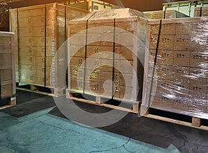 Worker driving forklift loading shipment carton boxes goods on wooden pallet at loading dock from container truck to warehouse car