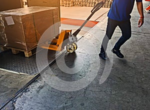 Worker driving forklift loading shipment carton boxes goods on wooden pallet at loading dock from container truck to warehouse car