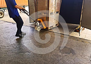 Worker driving forklift loading shipment carton boxes goods on wooden pallet at loading dock from container truck to warehouse car