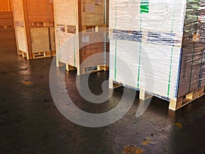 Worker driving forklift loading shipment carton boxes goods on wooden pallet at loading dock from container truck to warehouse car