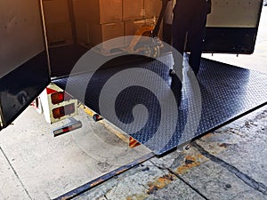 Worker driving forklift loading shipment carton boxes goods on wooden pallet at loading dock from container truck to warehouse car