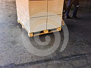 Worker driving forklift loading shipment carton boxes goods on wooden pallet at loading dock from container truck to warehouse car