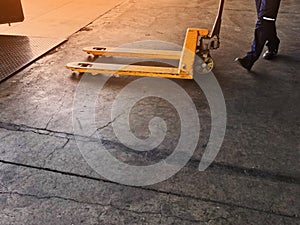 Worker driving forklift loading shipment carton boxes goods on wooden pallet at loading dock from container truck to warehouse car