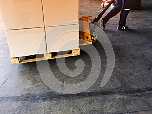 Worker driving forklift loading shipment carton boxes goods on wooden pallet at loading dock from container truck to warehouse car